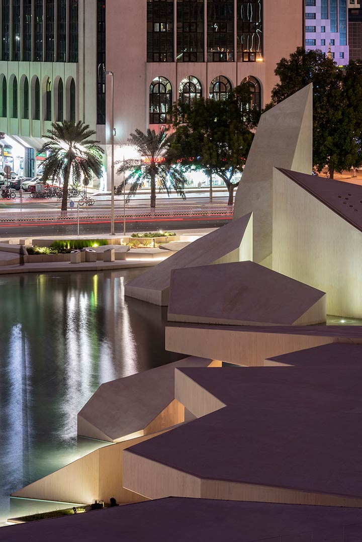 Nighttime view of the Al Musallah prayer hall in Abu Dhabi designed by CEBRA Architecture reflected at a water feature