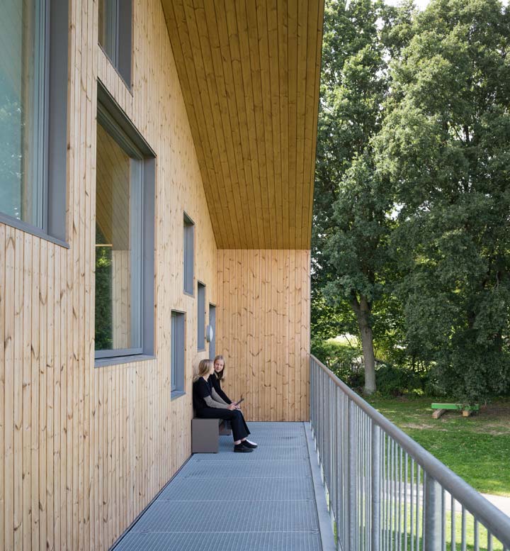 Two students sitting in an outdoor wooden sheltered gable at Skovbakke School. 