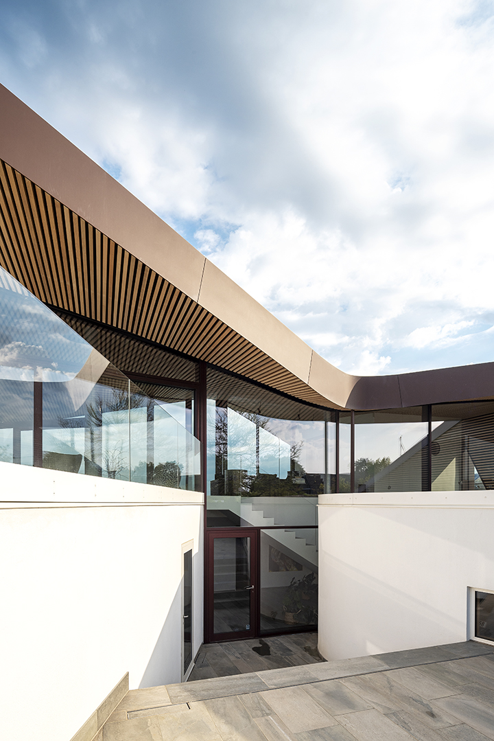 the protruding eaves of the undulating roof reduce the thermal stress on the glass facades and create generous roofed outdoor areas protected from the elements